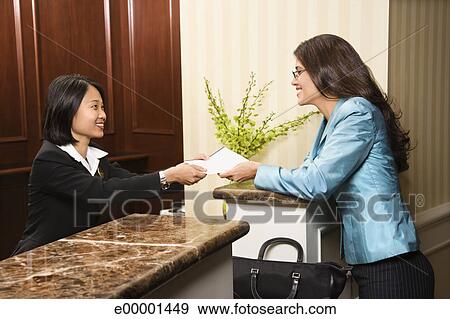 Woman Hotel Desk Clerk Handing Paperwork To Guest Stock Photo