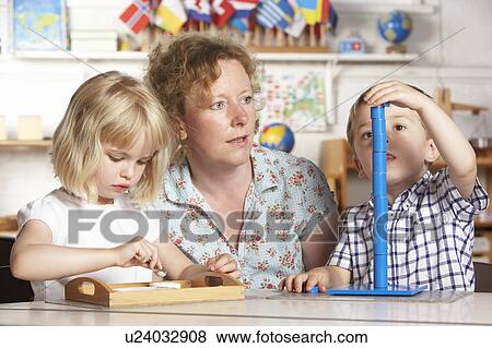 Stock Photo - Adult Helping Two Young Children at Montessori/Pre-School. Fotosearch