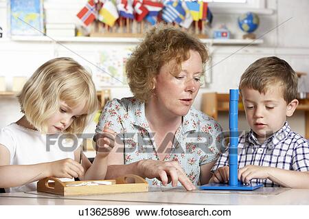 Adult Helping Two Young Children at Montessori/Pre-School View Large Photo Image Stock Photograph - Adult Helping Two Young Children at Montessori/Pre-School. Fotosearch