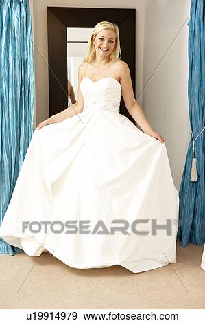 Stock Photo - Bride trying on wedding dress. Fotosearch