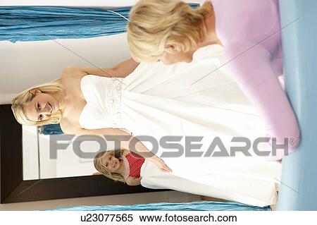 Bride trying on wedding dress with sales assistant View Large Photo Image Stock Photography - Bride trying on wedding dress with sales assistant. Fotosearch