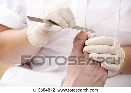 Stock Image - Chirpodist treating client in clinic. Fotosearch