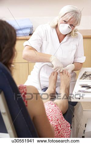 Stock Image - Chirpodist treating client in clinic. Fotosearch