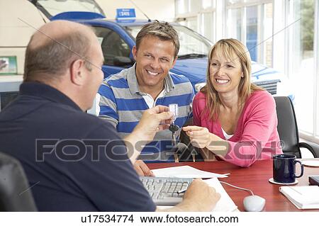 Couple filling in paperwork in car showroom View Large Photo Image Picture - Couple filling in paperwork in car showroom. Fotosearch