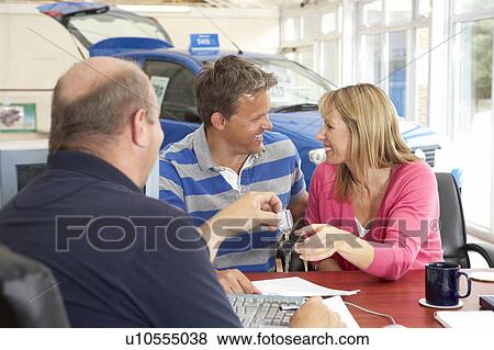 Couple filling in paperwork in car showroom View Large Photo Image Stock Photo - Couple filling in paperwork in car showroom. Fotosearch