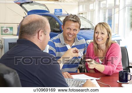 Couple filling in paperwork in car showroom View Large Photo Image Stock Photo - Couple filling in paperwork in car showroom. Fotosearch