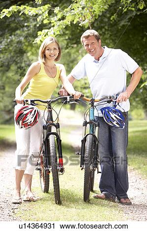 Stock Image - Couple riding bikes in countryside. Fotosearch