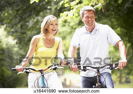 Stock Image - Couple riding bikes in countryside. Fotosearch