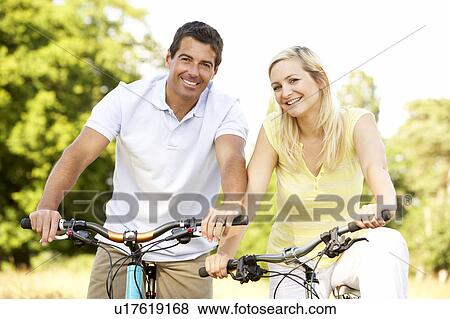 Stock Photo - Couple riding bikes in countryside. Fotosearch