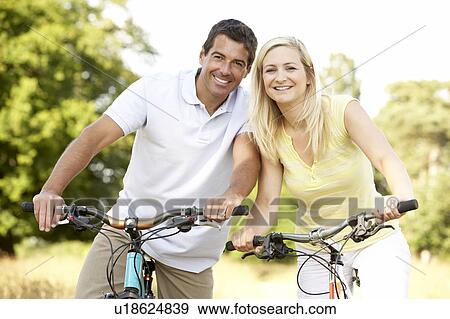 Couple riding bikes in countryside View Large Photo Image Stock Photo - Couple riding bikes in countryside. Fotosearch