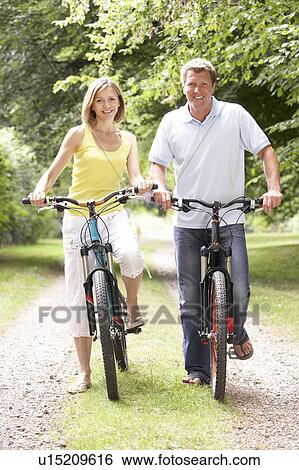 Stock Photograph - Couple riding bikes in countryside. Fotosearch