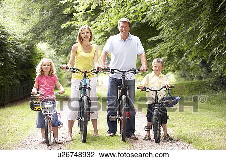 Stock Image - Family riding bikes in countryside. Fotosearch