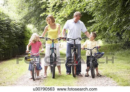 Stock Image - Family riding bikes in countryside. Fotosearch