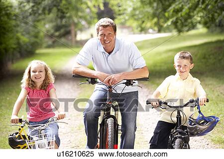 Stock Photography - Father and children riding bikes in countryside. Fotosearch