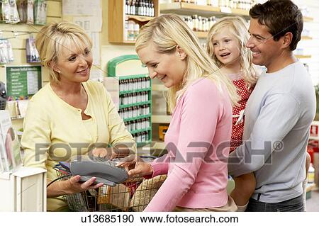 Stock Image - Female sales assistant in health food store. Fotosearch