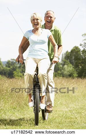 Mature couple riding bike in countryside View Large Photo Image Stock Image - Mature couple riding bike in countryside. Fotosearch