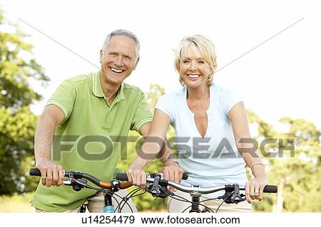 Stock Photo - Mature couple riding bikes. Fotosearch