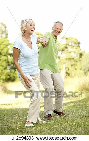 Mature couple walking in countryside View Large Photo Image Stock Image - Mature couple walking in countryside. Fotosearch