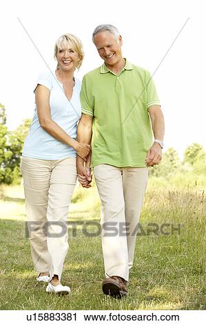 Stock Image - Mature couple walking in countryside. Fotosearch