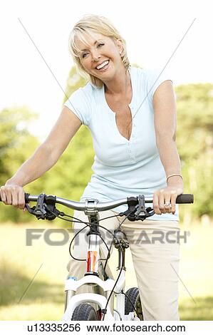 Portrait of mature woman riding cycle in countryside View Large Photo Image Stock Photograph - Portrait of mature woman riding cycle in countryside. Fotosearch