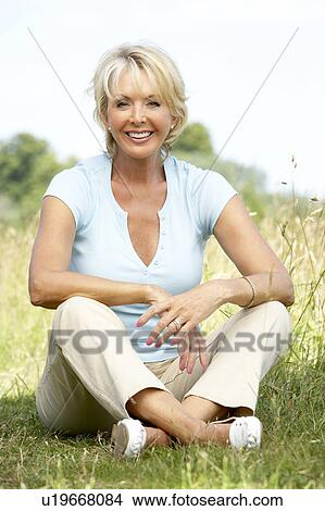 Picture - Portrait of mature woman sitting in countryside. Fotosearch