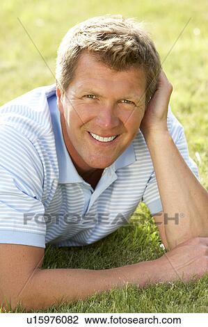 Stock Image - Portrait of young man relaxing in countryside. Fotosearch