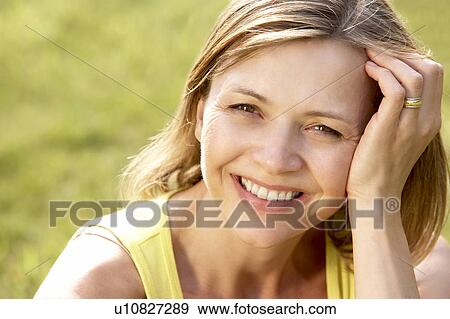Stock Photo - Portrait of young woman relaxing in countryside. Fotosearch