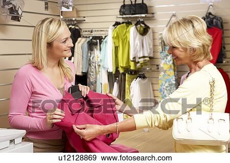 Stock Photo - Sales assistant with customer in clothing store. Fotosearch