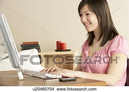 Picture - Smiling Teenage Girl on Computer at Home. Fotosearch