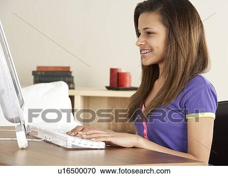 Stock Image - Smiling Teenage Girl on Computer at Home. Fotosearch