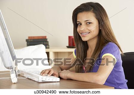 Stock Image - Smiling Teenage Girl on Computer at Home. Fotosearch