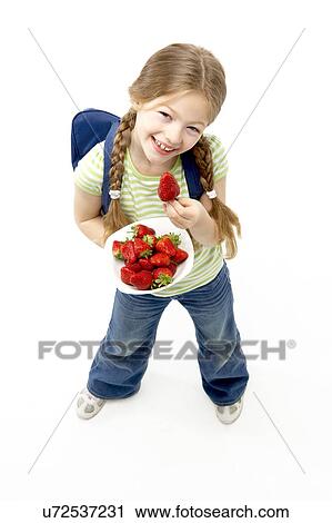 Stock Image - Studio Portrait of Smiling Girl Holding Bowl of Strawberries. Fotosearch