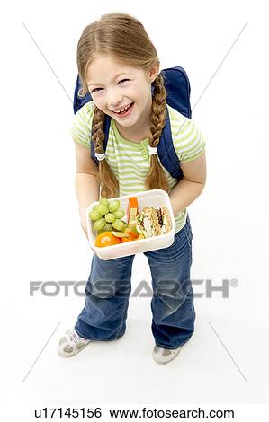 Stock Photograph - Studio Portrait of Smiling Girl Holding Lunchbox. Fotosearch