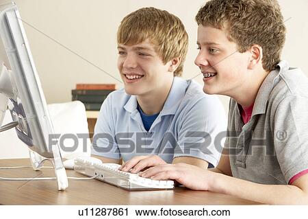 Stock Image - Two Teenage Boys on Computer at Home. Fotosearch