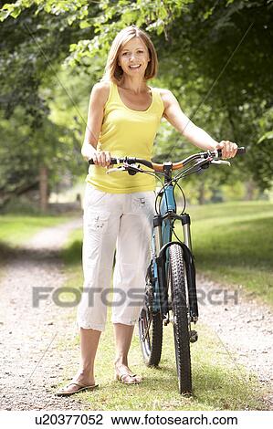 Stock Image - Woman riding bike in countryside. Fotosearch