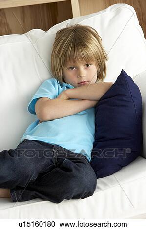 Stock Image - Young Boy Sat on Sofa at Home. Fotosearch