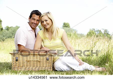 Stock Image - Young couple having picnic in countryside. Fotosearch