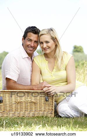 Stock Image - Young couple having picnic in countryside. Fotosearch