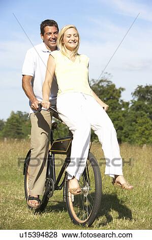 Young couple riding bike in countryside View Large Photo Image Stock Photo - Young couple riding bike in countryside. Fotosearch