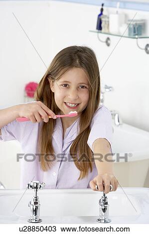 Stock Image - Young Girl Brushing Teeth at Sink. Fotosearch