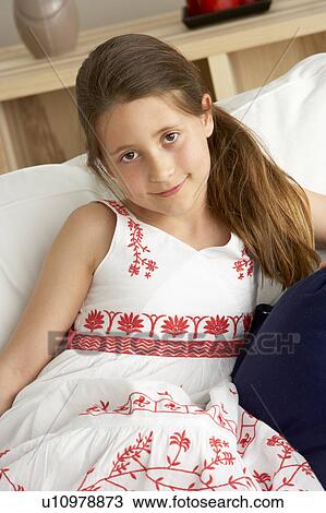 Stock Image - Young Girl Sat on Sofa at Home. Fotosearch