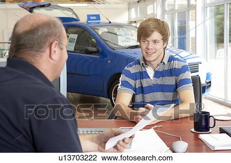 Young man filling in paperwork in car showroom View Large Photo Image Stock Image - Young man filling in paperwork in car showroom. Fotosearch