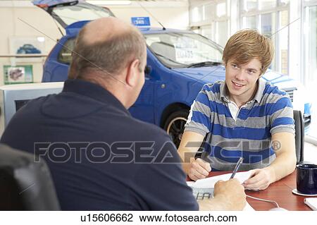 Young man filling in paperwork in car showroom View Large Photo Image Stock Image - Young man filling in paperwork in car showroom. Fotosearch