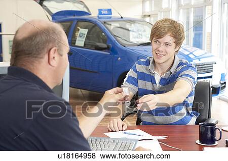 Young man filling in paperwork in car showroom View Large Photo Image Stock Photo - Young man filling in paperwork in car showroom. Fotosearch