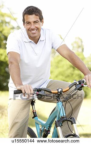Picture - Young man riding bike in countryside. Fotosearch