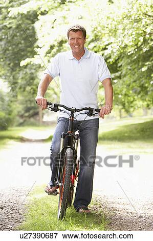 Stock Photo - Young man riding bike in countryside. Fotosearch