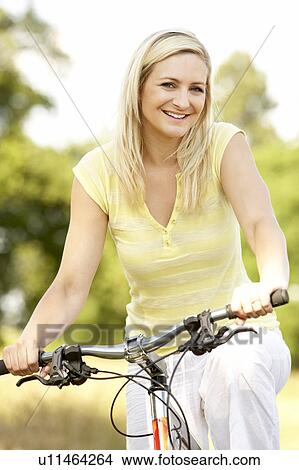 Young woman riding bike in countryside View Large Photo Image Picture - Young woman riding bike in countryside. Fotosearch