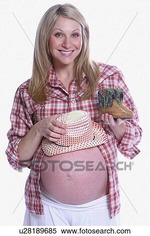 Stock Photography - Pregnant lady with tiny cowboy boots and cowboy hat. Fotosearch
