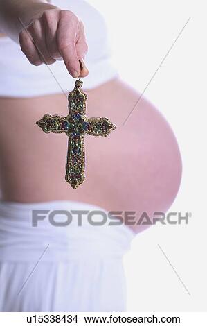 Pregnant woman holding a cross View Large Photo Image Picture - Pregnant woman holding a cross. Fotosearch