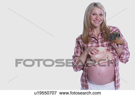 Stock Photo - Pregnant woman holding little clothes. Fotosearch